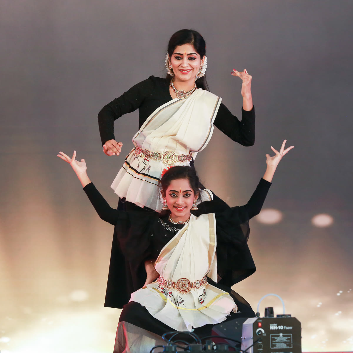 Two dancers in white and gold holding a classical pose on stage
