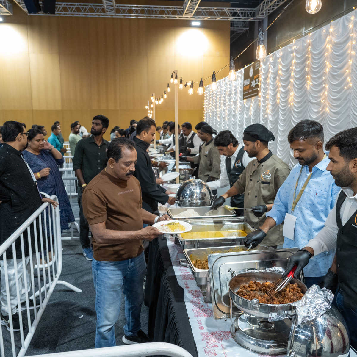 Volunteers serving from steel chafing dishes along a buffet counter at a community meal