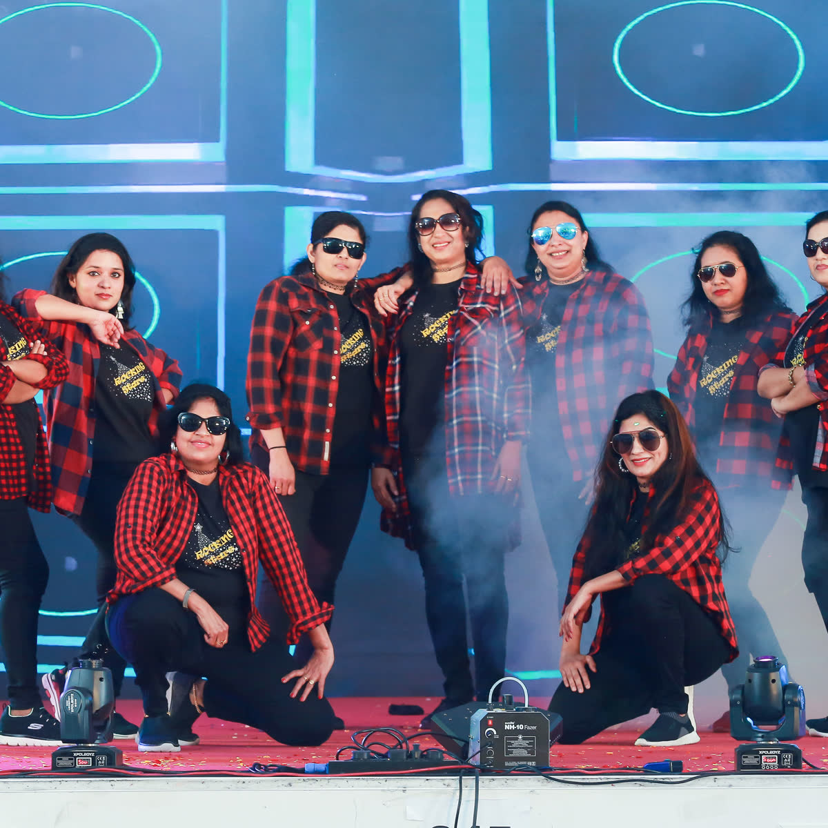 A group of members in matching red and black shirts posing together on stage