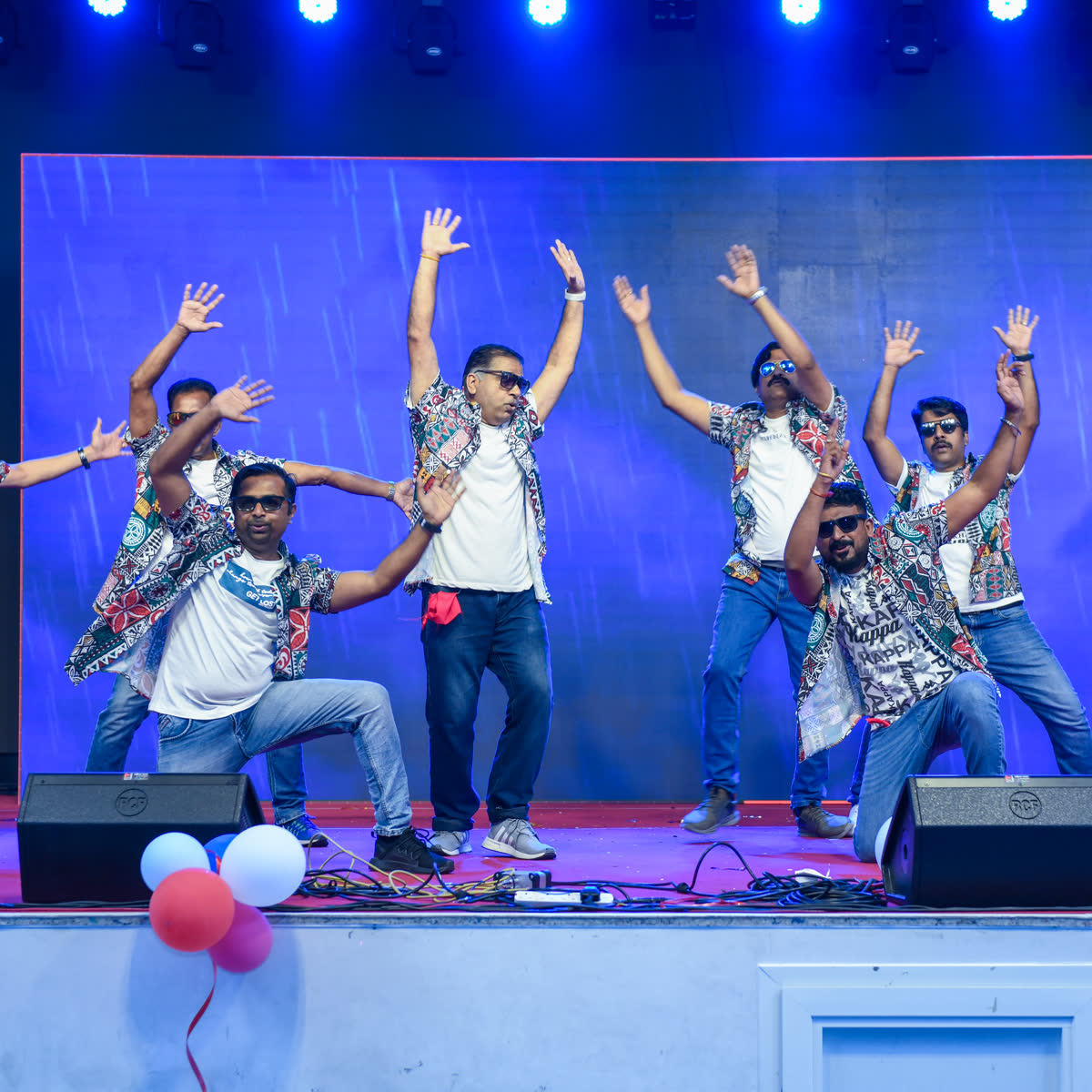 Performers with arms raised in celebration at the end of a stage item
