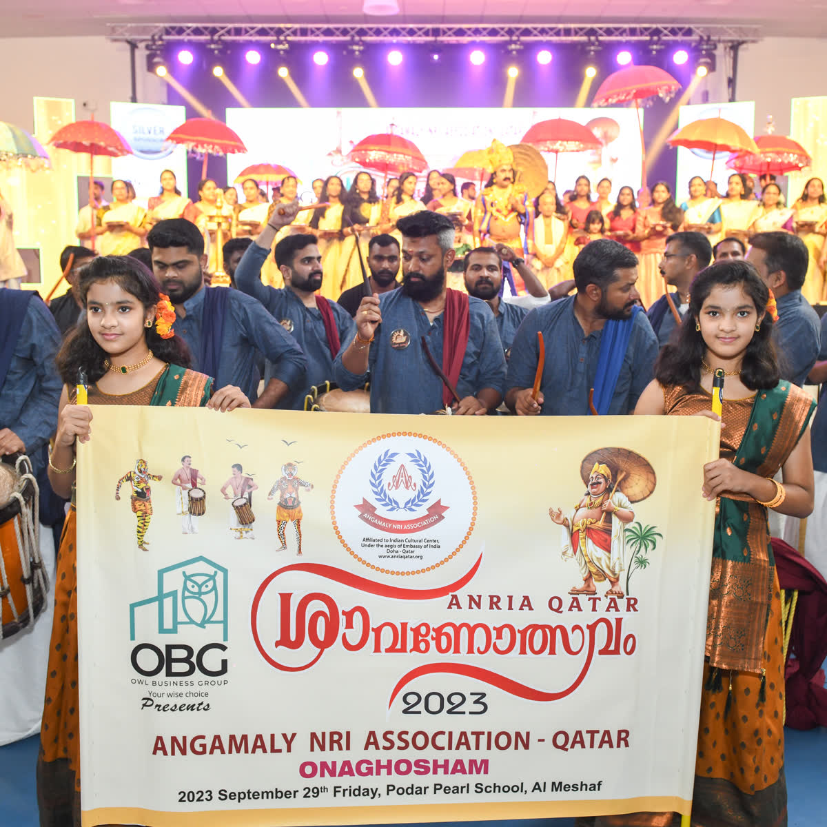 Members with chenda drums beside the ANRIA Qatar Onaghosham 2023 banner