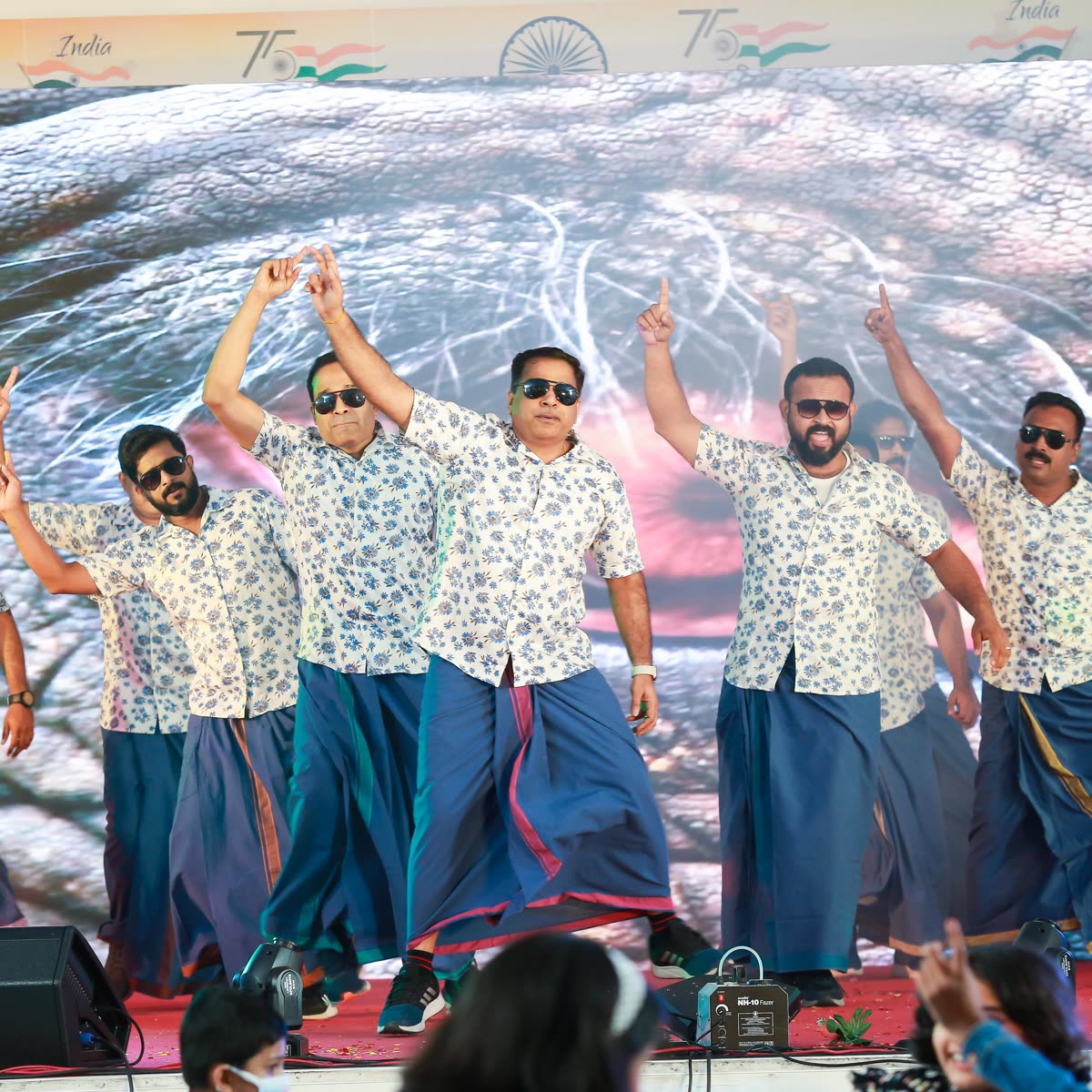 Dancers with arms raised in unison during an Onam stage performance