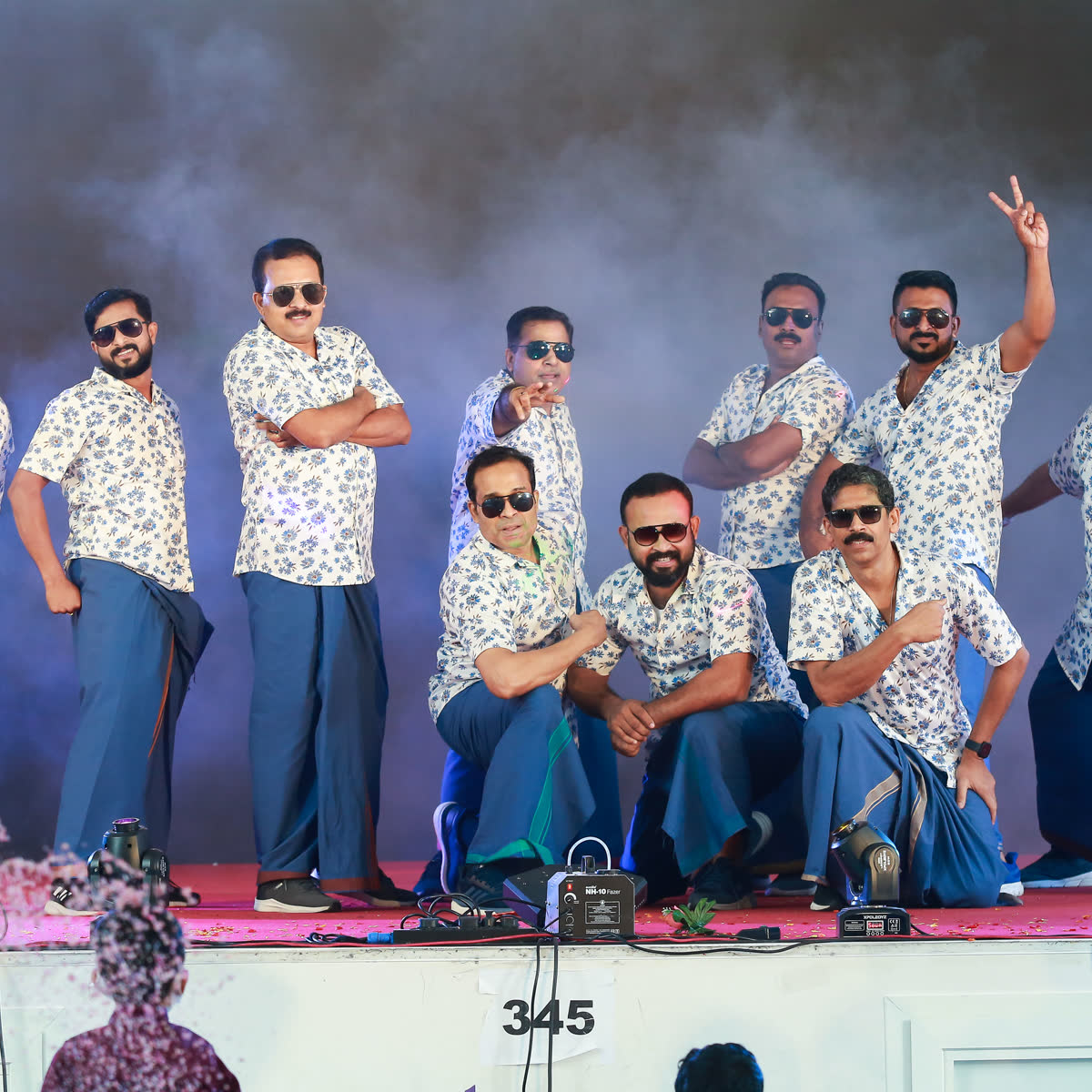 A team of men in matching printed shirts posing on stage after their performance