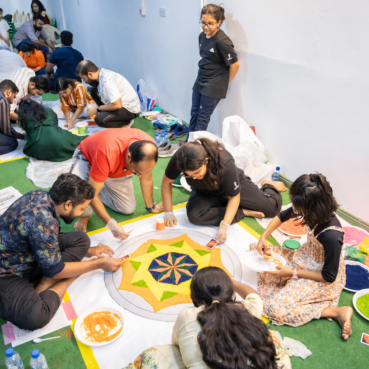 Several pookalam designs taking shape on the floor as members work on them together