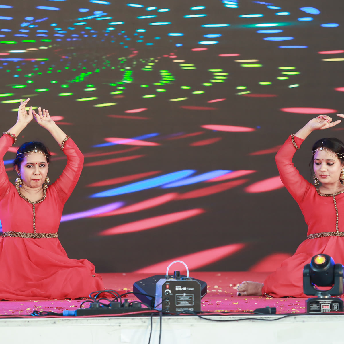 A dancer in red performing solo against a brightly patterned LED backdrop
