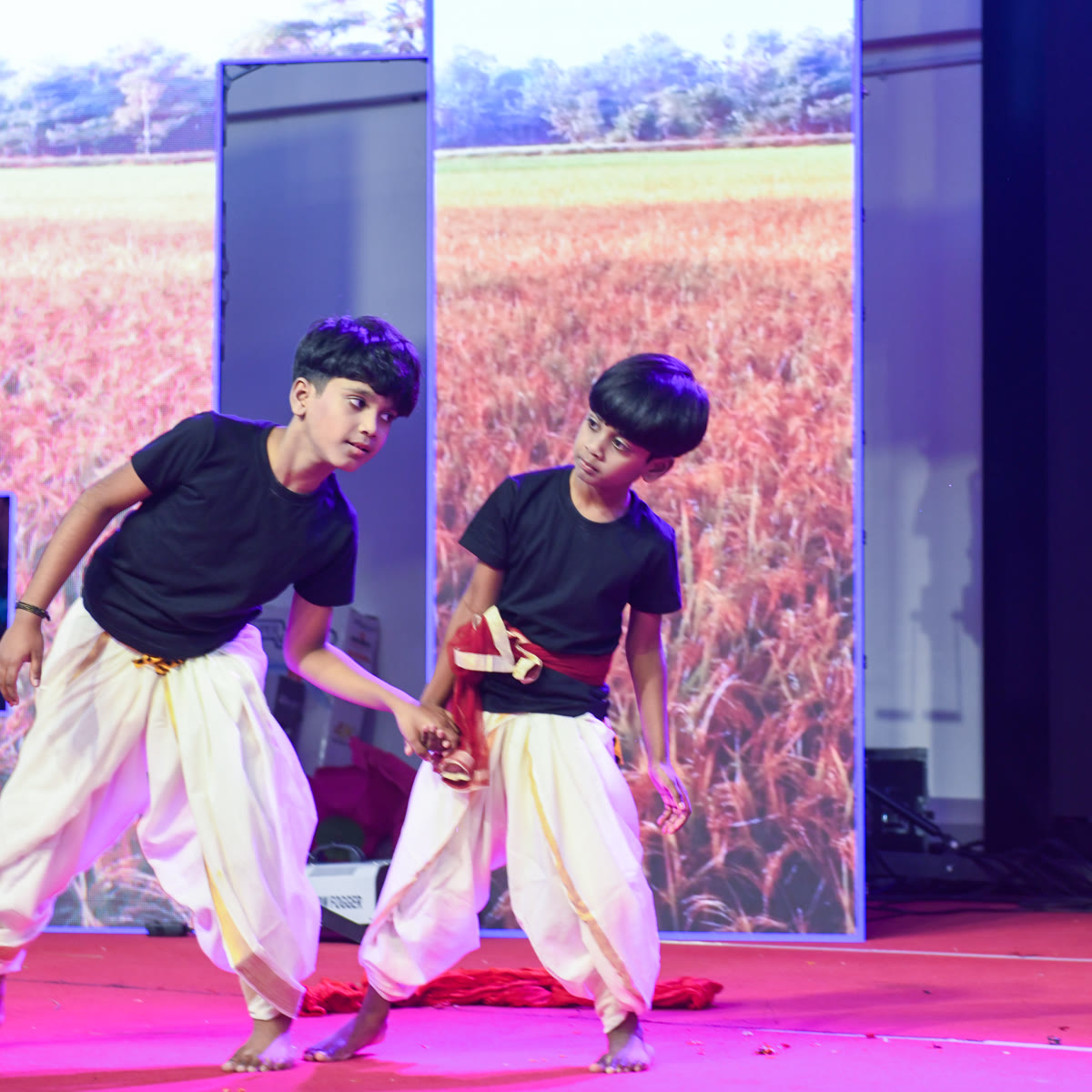 Two young performers dancing in front of a field backdrop